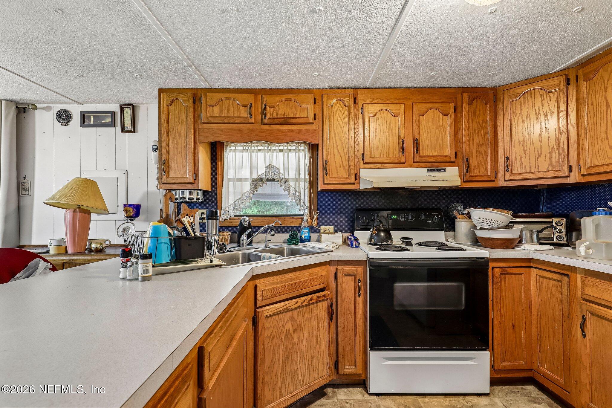 9690 Black Jack Road Macclenny, FL 32063 - Photo 13 of 34 a kitchen with stainless steel appliances granite countertop a stove a sink and a microwave