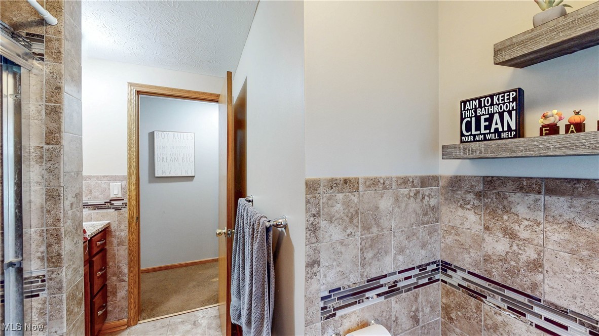 3123 Clearview Road Ravenna, OH 44266 - Photo 25 of 44 Full bathroom with vanity, tile walls, and a textured ceiling