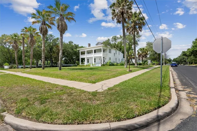 a view of a house with a yard and large trees