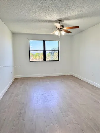 an empty room with windows and fan