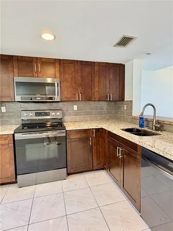 a kitchen with stainless steel appliances granite countertop a stove a sink and a microwave