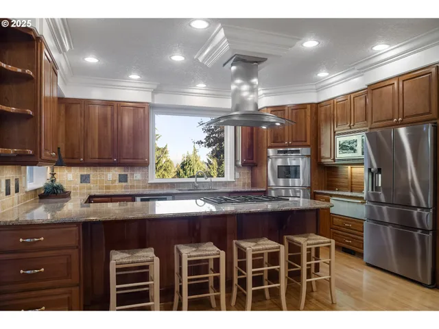 a kitchen with kitchen island granite countertop wooden cabinets and stainless steel appliances