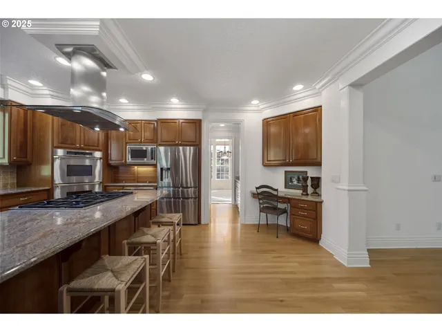 a kitchen with stainless steel appliances a refrigerator a stove a sink a oven with wooden cabinets and wooden floor