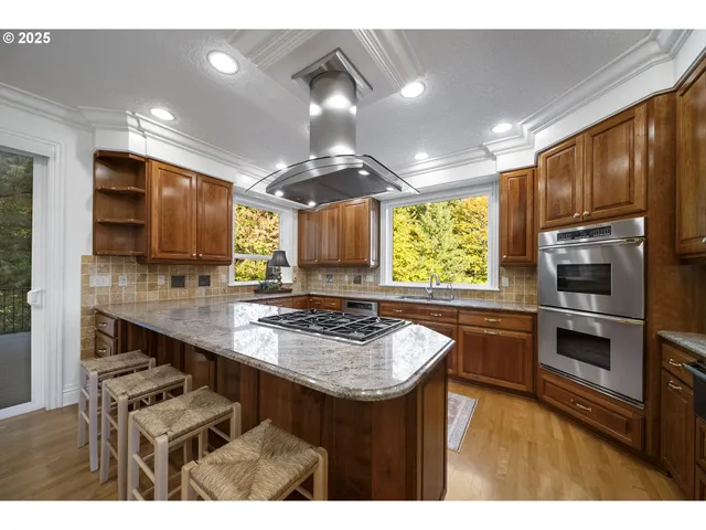 a kitchen with stainless steel appliances kitchen island granite countertop a sink stove and refrigerator