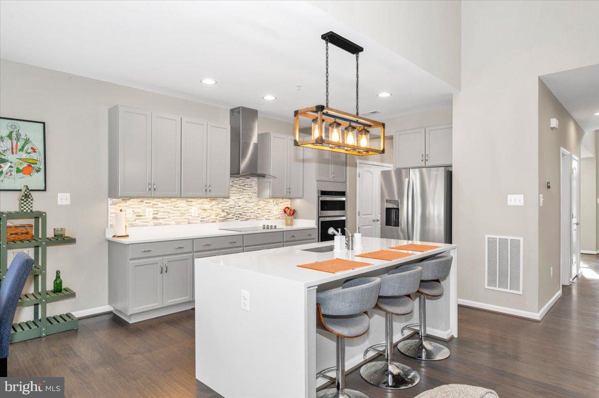 7796 Old Receiver Road Frederick, MD 21702 - Photo 4 of 65 a kitchen with stainless steel appliances kitchen island granite countertop a sink a stove a refrigerator and a dining table with wooden floor