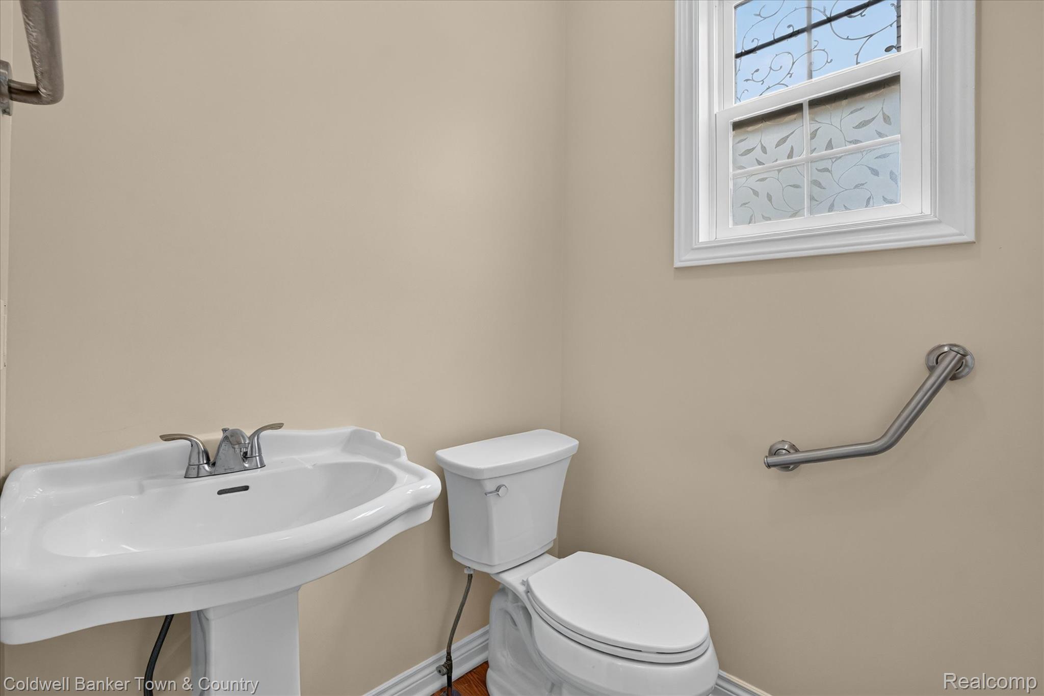 1725 Town Commons Drive Howell, MI 48855 - Photo 28 of 53 Pedestal sink with chrome faucet, standard toilet, and a window featuring decorative privacy film