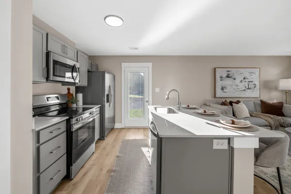 a kitchen with stainless steel appliances kitchen island granite countertop a sink stove and refrigerator