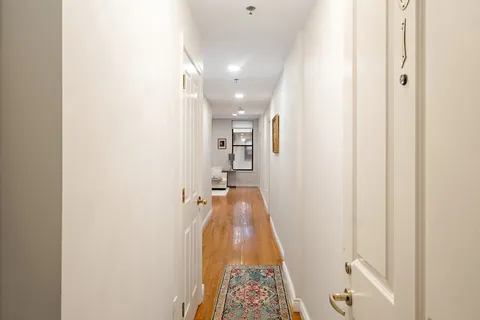 a view of a hallway with wooden floor and a bathroom