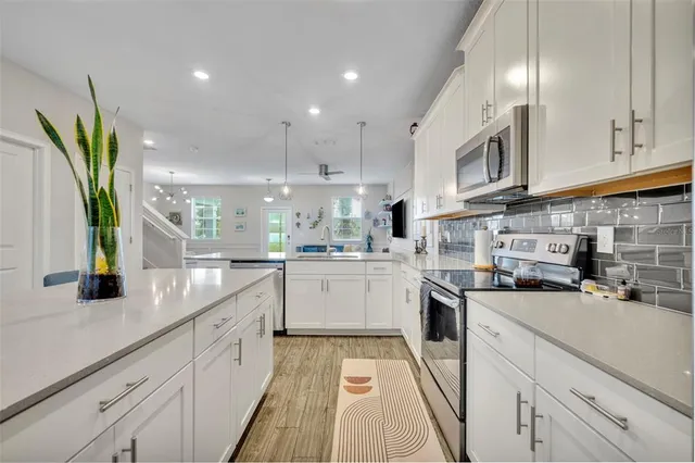 a kitchen with a sink stainless steel appliances cabinets and a window