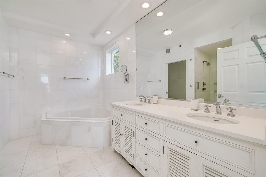 217 Hendricks Isle, Unit 402 Fort Lauderdale, FL 33301 - Photo 12 of 39 a bathroom with a double vanity sink a mirror and a bathtub