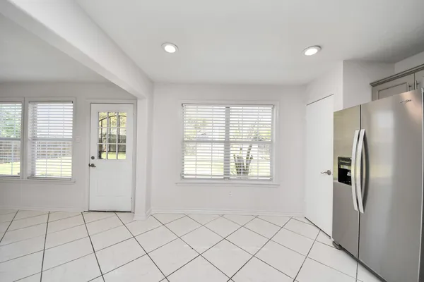 a view of an empty room with window and refrigerator