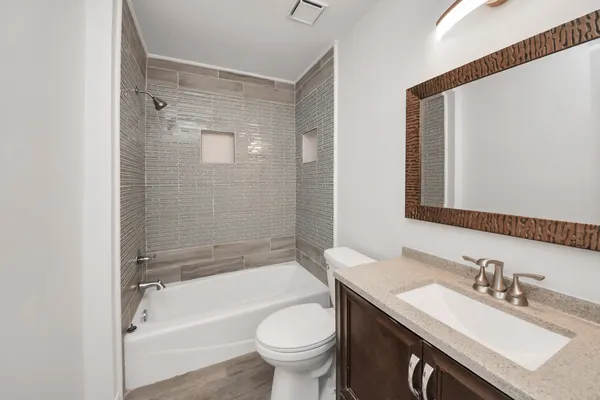 a bathroom with a bathtub shower sink vanity mirror and toilet