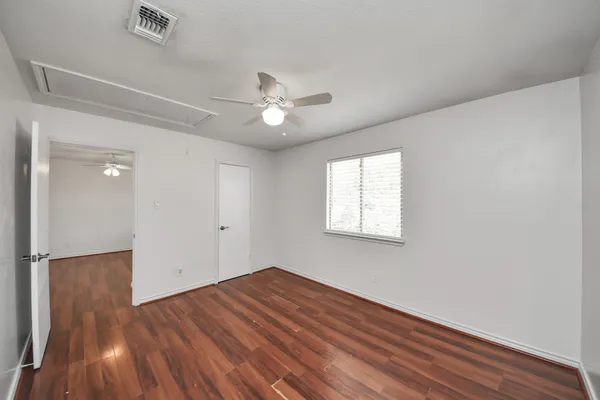 a view of empty room with wooden floor and fan