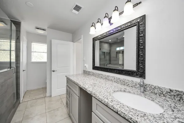 a bathroom with a granite countertop sink a large mirror and a shower