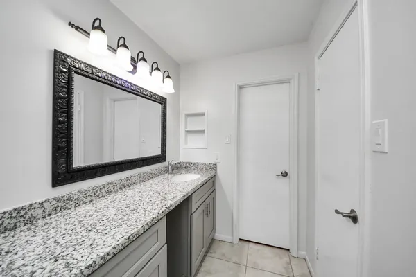 a bathroom with a granite countertop sink and a mirror