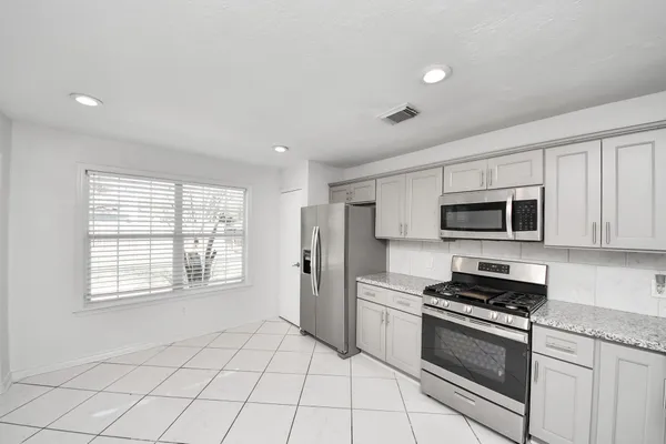 a kitchen with stainless steel appliances granite countertop a stove a sink and a refrigerator