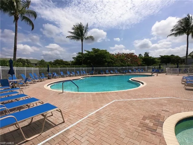 a view of swimming pool with seating space and trees in the background