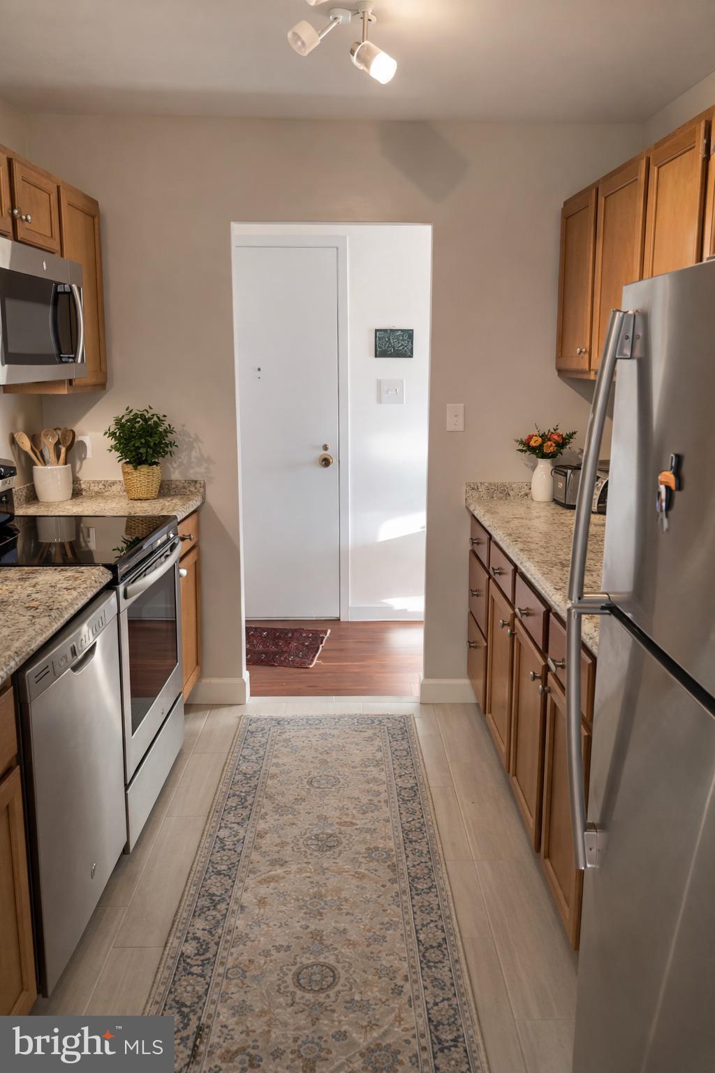 9701 Fields Road, Unit 1808 Gaithersburg, MD 20878 - Photo 4 of 11 a kitchen with granite countertop a sink stove and refrigerator
