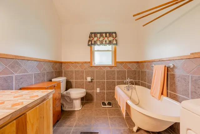 an aerial view of a residential houses with outdoor space and trees all around