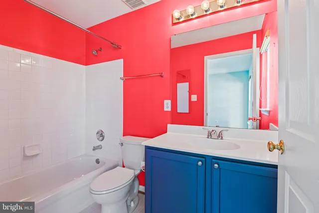 a bathroom with a bath tub sink mirror vanity and toilet
