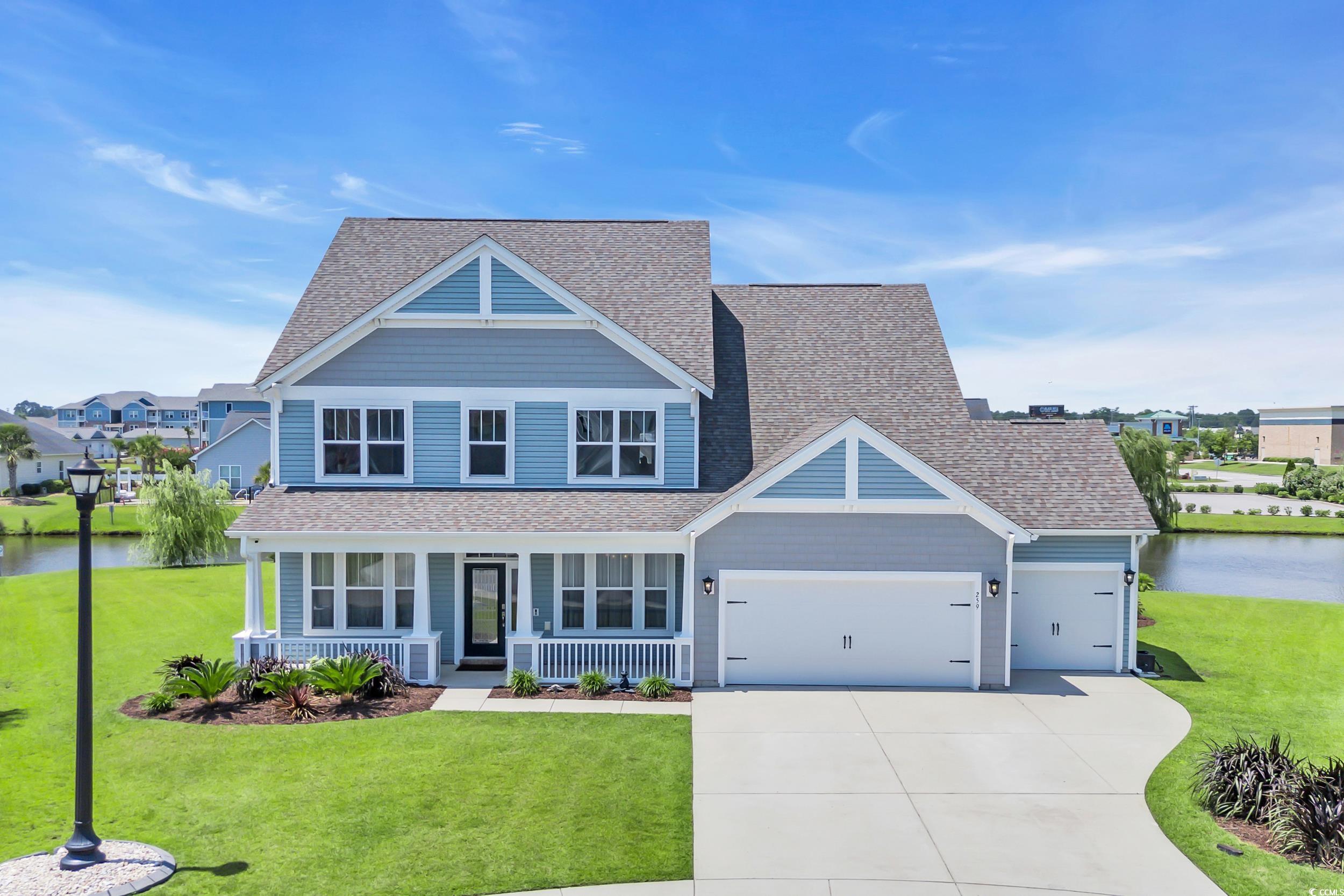View of front of property featuring covered porch, a shingled roof, a garage, concrete driveway, and a front lawn
