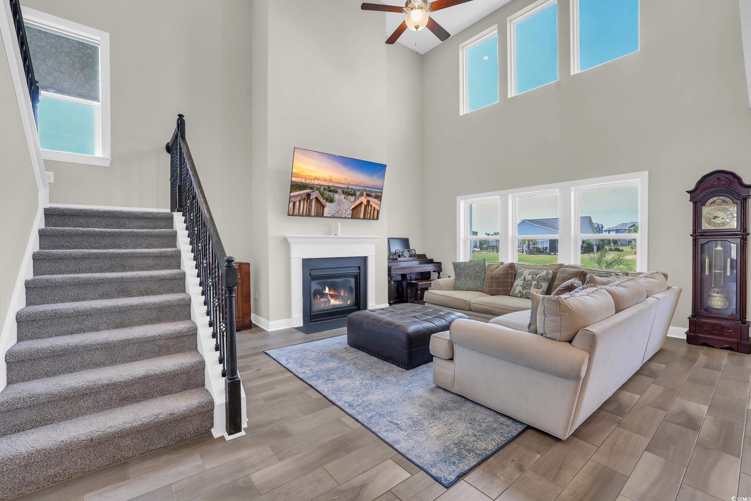 259 Hull Street Surfside Beach, SC 29575 - Photo 15 of 40 Living room with a high ceiling, stairway, ceiling fan, wood finished floors, and a fireplace with flush hearth