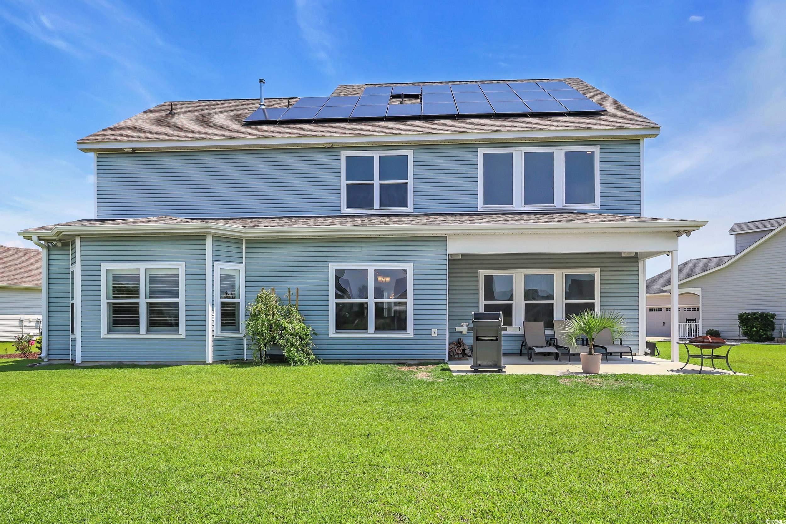 259 Hull Street Surfside Beach, SC 29575 - Photo 36 of 40 Rear view of house with a patio area, solar panels, a yard, and a shingled roof
