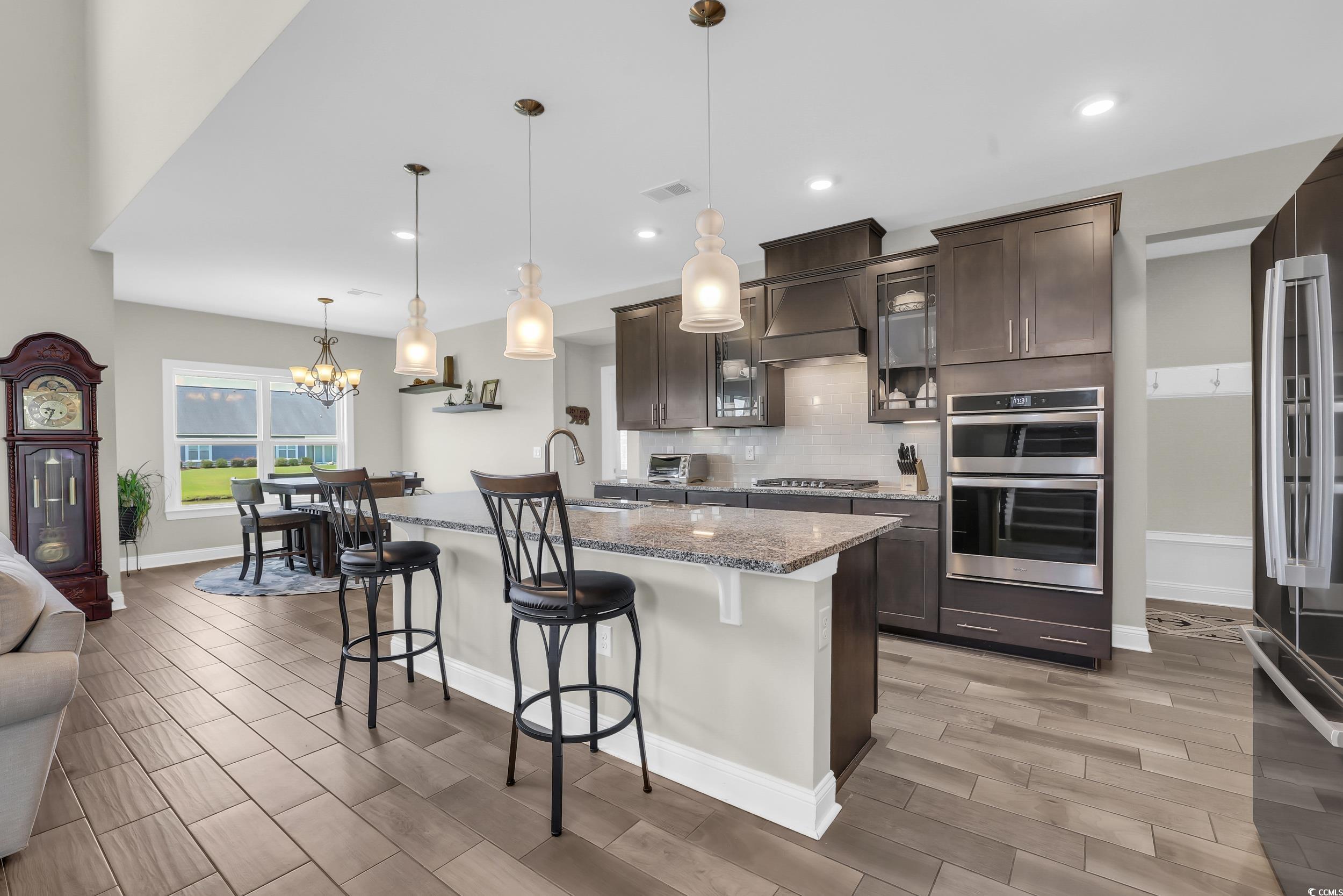 259 Hull Street Surfside Beach, SC 29575 - Photo 7 of 40 Kitchen with stainless steel appliances, a kitchen breakfast bar, dark brown cabinets, decorative backsplash, and recessed lighting