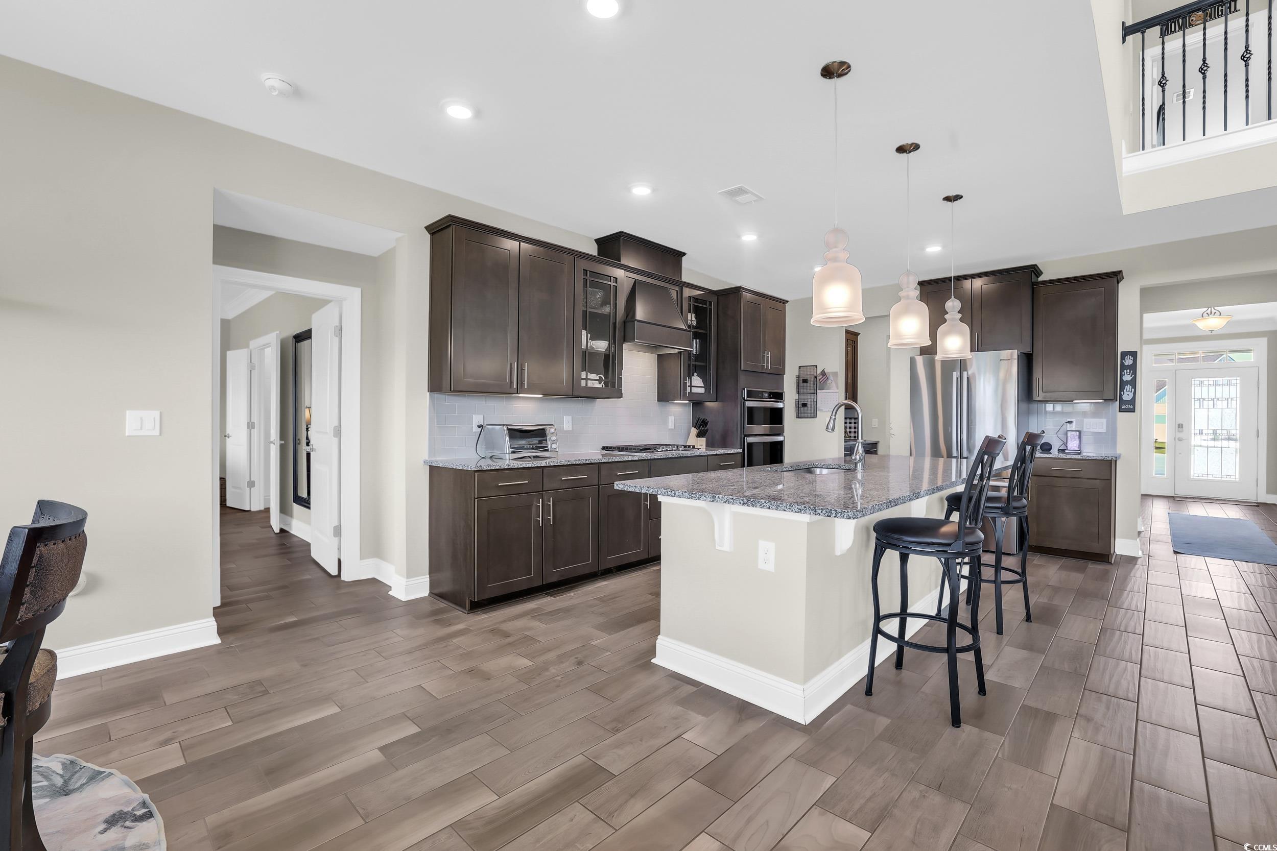 259 Hull Street Surfside Beach, SC 29575 - Photo 8 of 40 Kitchen with dark brown cabinetry, a kitchen breakfast bar, light wood-type flooring, stainless steel appliances, and recessed lighting