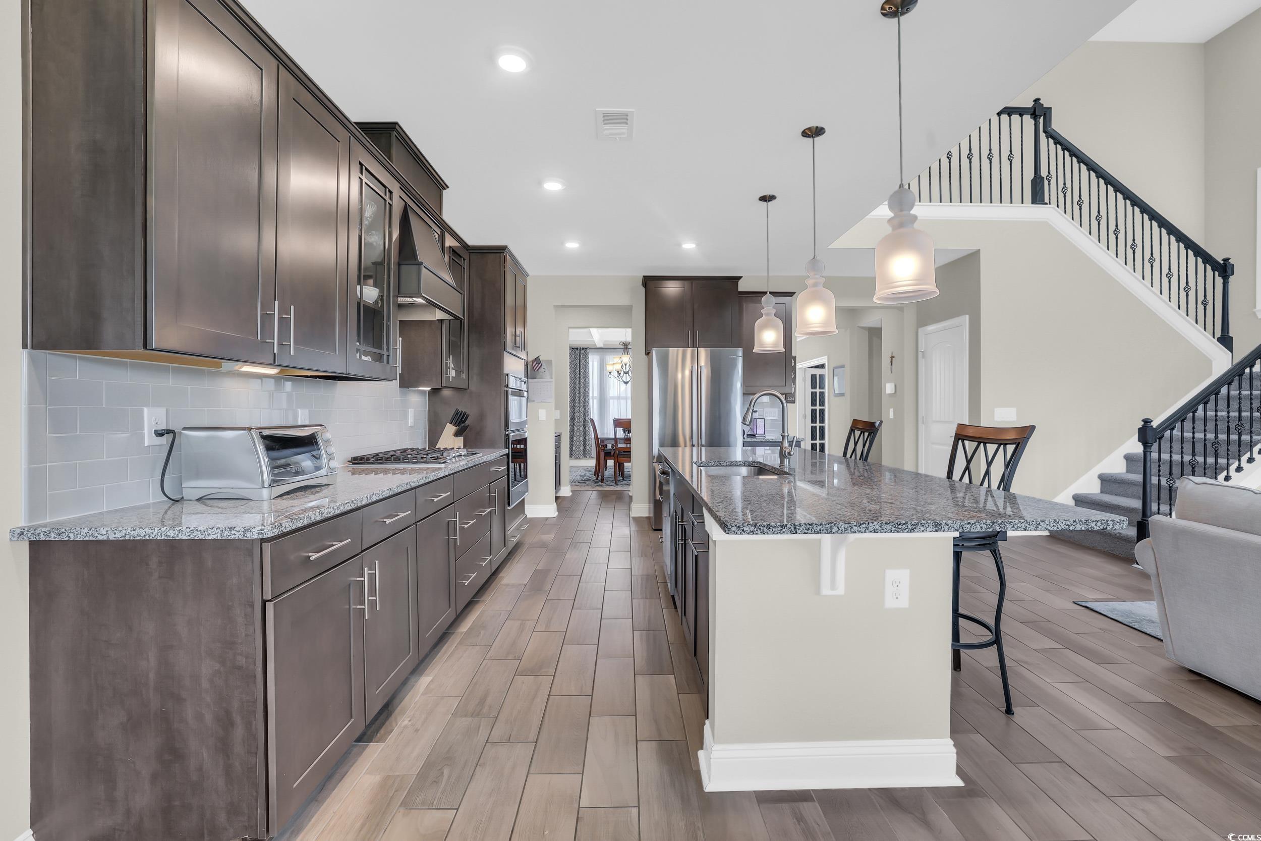 259 Hull Street Surfside Beach, SC 29575 - Photo 9 of 40 Kitchen featuring a kitchen bar, dark brown cabinets, appliances with stainless steel finishes, light wood-type flooring, and recessed lighting