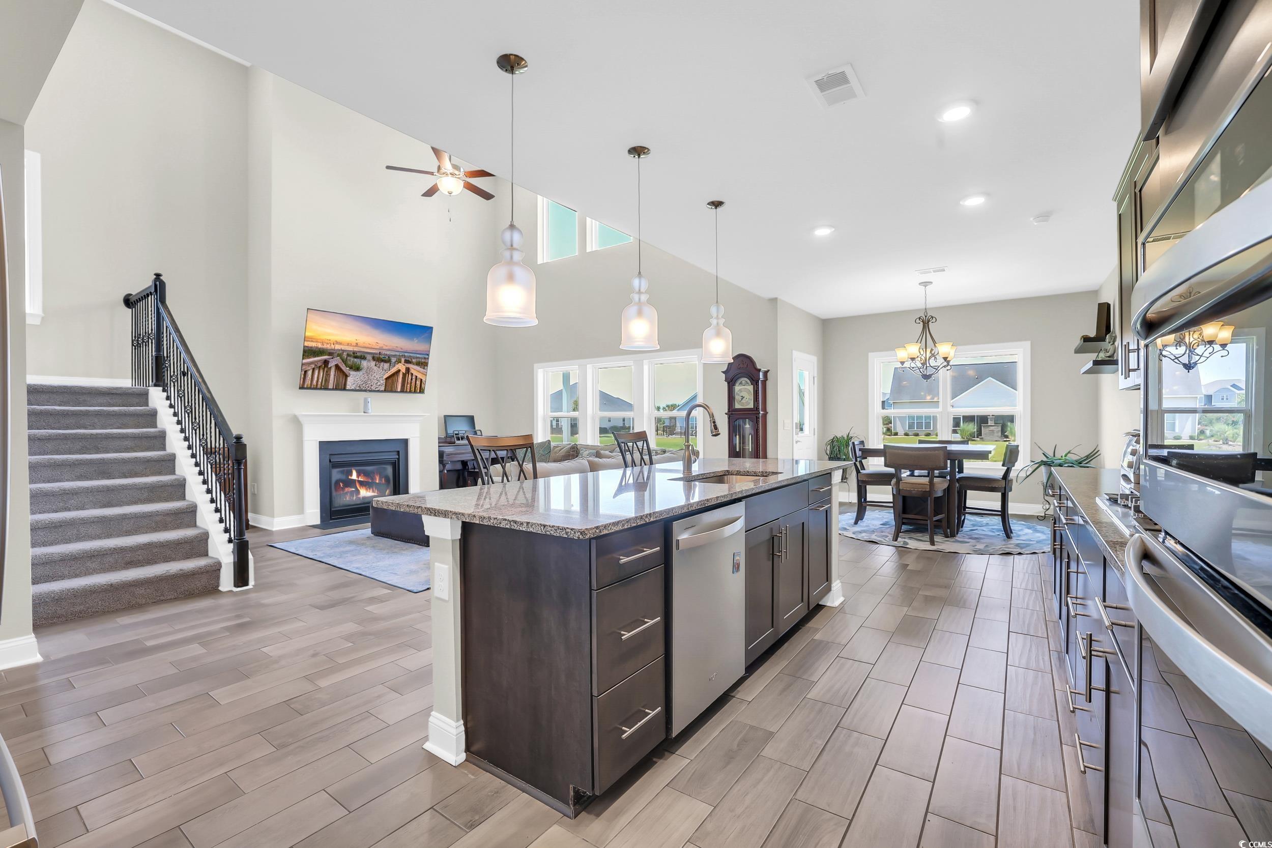 259 Hull Street Surfside Beach, SC 29575 - Photo 10 of 40 Kitchen with appliances with stainless steel finishes, wood finish floors, a glass covered fireplace, dark brown cabinetry, and light stone counters