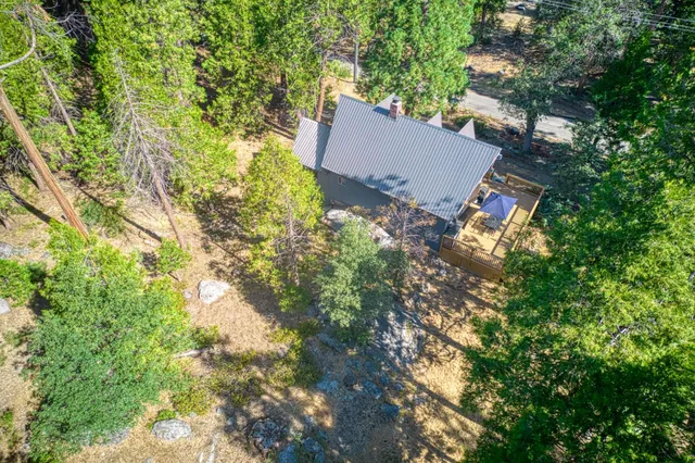 an aerial view of residential house with outdoor space and trees all around