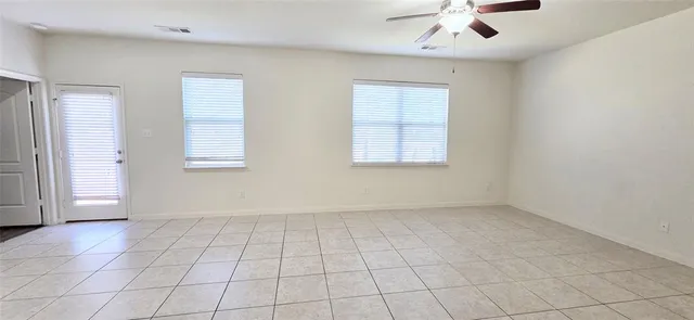 an empty room with windows and ceiling fan