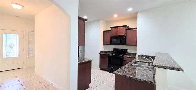 a kitchen with granite countertop a stove top oven microwave and sink