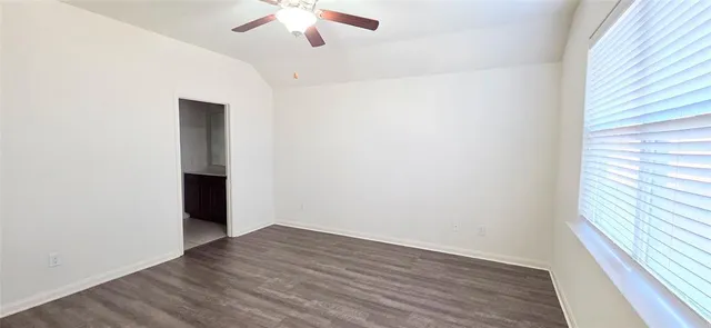 an empty room with wooden floor chandelier fan and windows