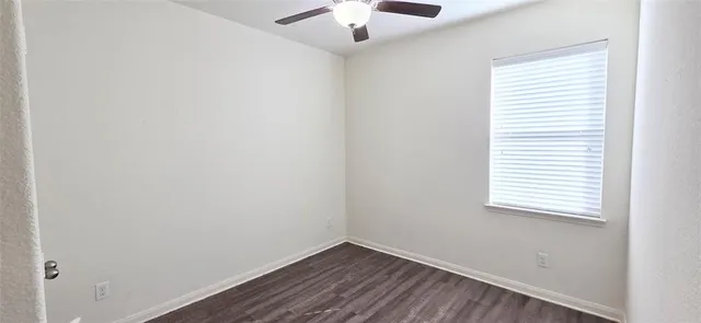 an empty room with a window and a chandelier fan