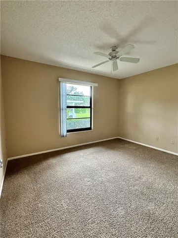 an empty room with windows and ceiling fan