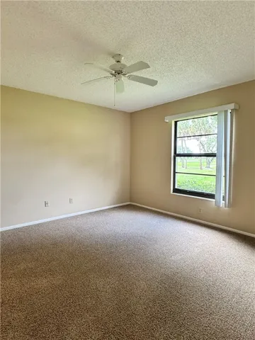 an empty room with a window and a ceiling fan