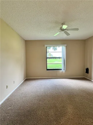 an empty room with a window and a ceiling fan