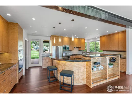 a kitchen with stainless steel appliances kitchen island granite countertop a refrigerator a stove a sink and a dining table with wooden floor