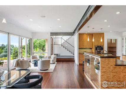 a living room with stainless steel appliances kitchen island granite countertop a stove a sink dishwasher and a dining table with wooden floor