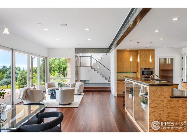 a living room with stainless steel appliances kitchen island granite countertop a stove a sink dishwasher and a dining table with wooden floor