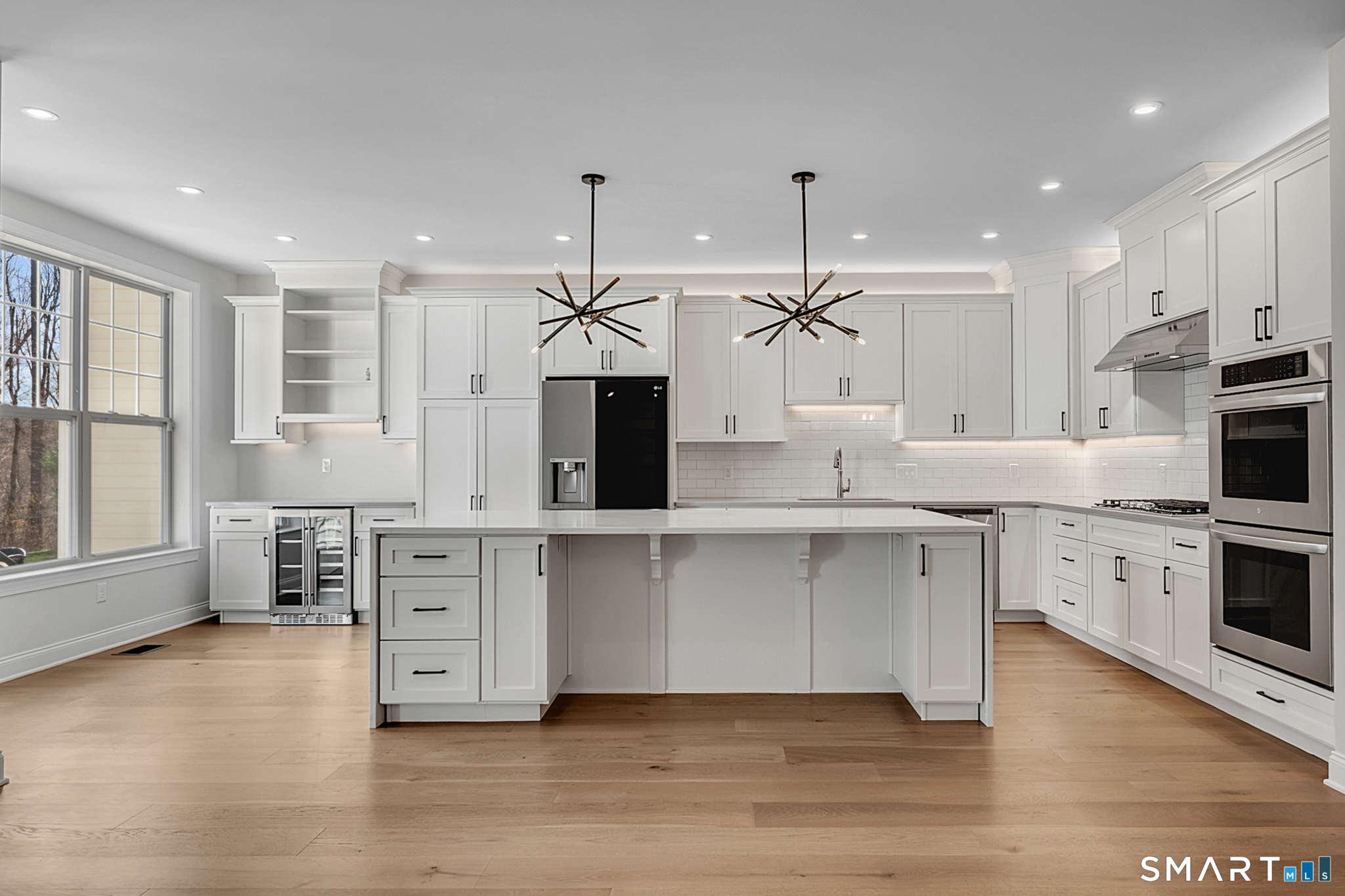 193 Ridgewood Drive, Unit 193 Middlebury, CT 06762 - Photo 12 of 40 a large white kitchen with granite countertop a stove a sink a refrigerator and white cabinets with wooden floor