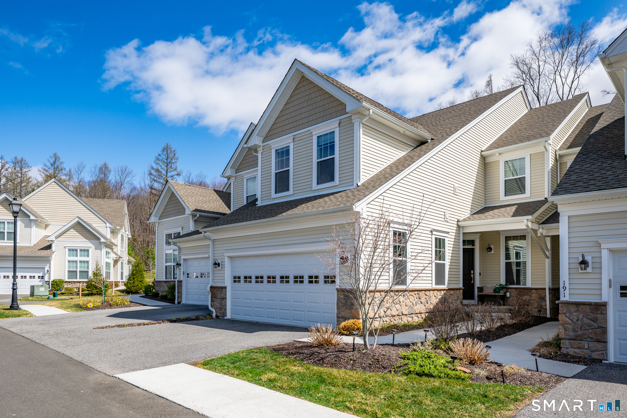 193 Ridgewood Drive, Unit 193 Middlebury, CT 06762 - Photo 2 of 40 a view of a white house with large windows and a table and chairs under an umbrella