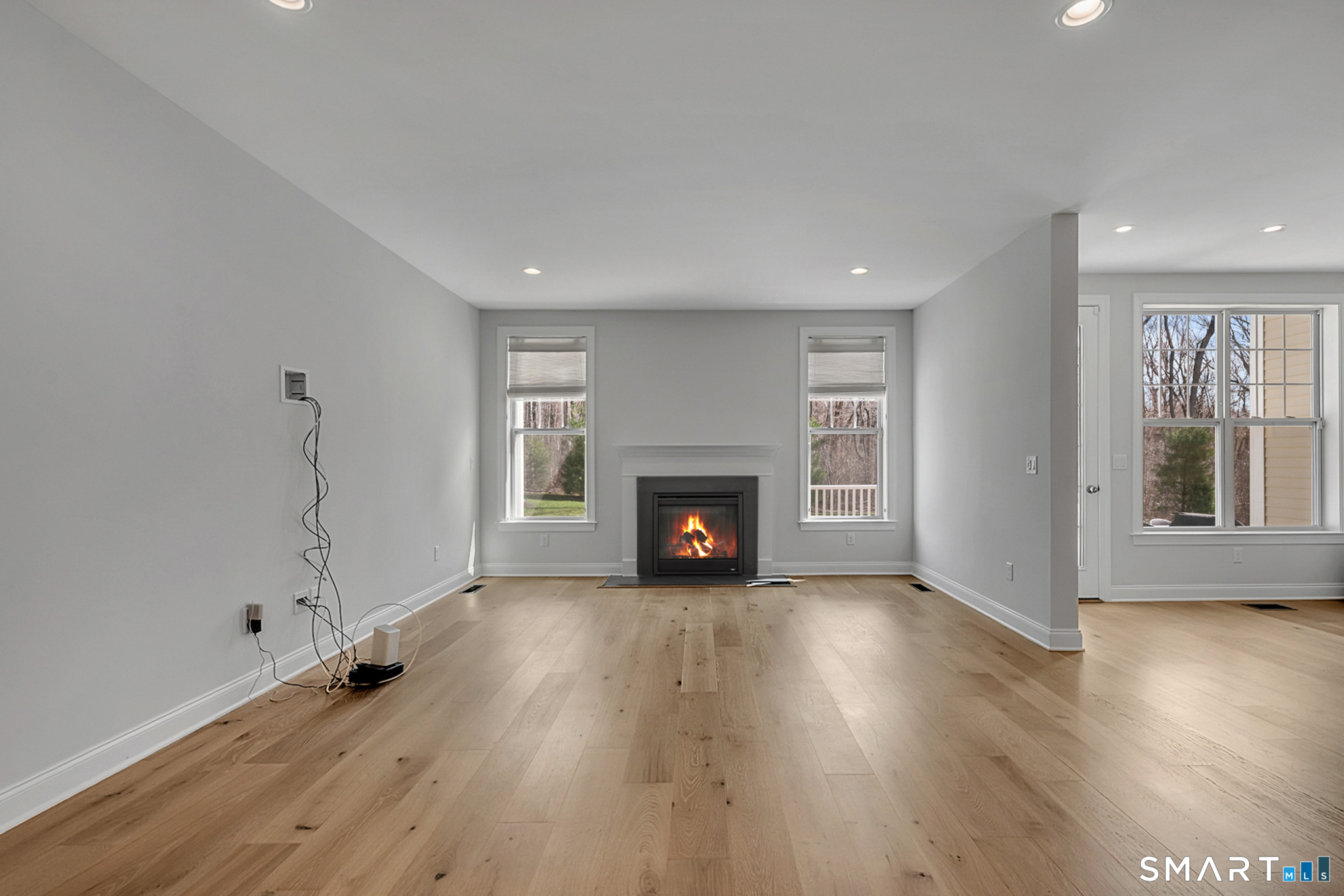 193 Ridgewood Drive, Unit 193 Middlebury, CT 06762 - Photo 9 of 40 an empty room with wooden floor fireplace and windows