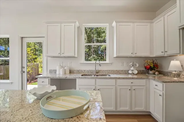a kitchen with granite countertop a sink a window and cabinets