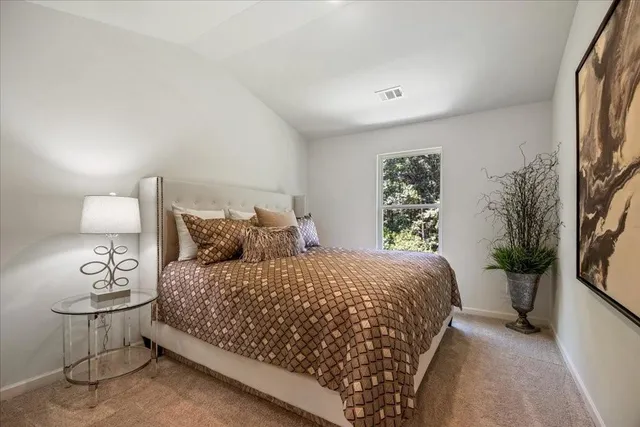 a large bed sitting in a bedroom next to a window with potted plant