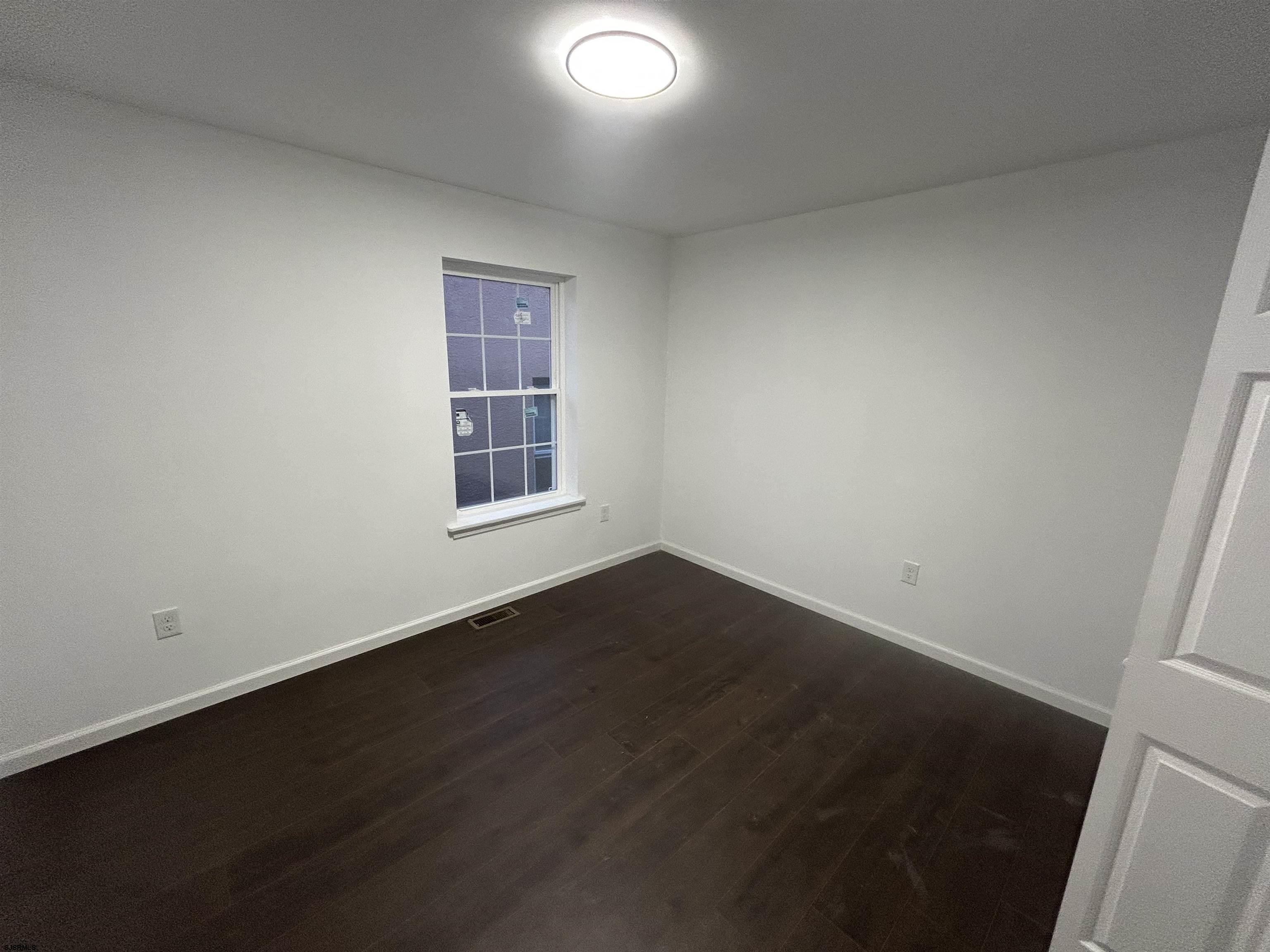 2821 Arctic Avenue, Unit 3 Atlantic City, NJ 08401 - Photo 7 of 11 an empty room with wooden floor and windows