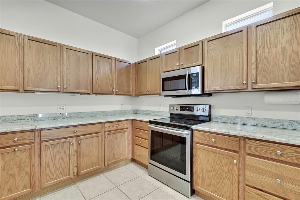 8049 Sanguinelli Road Land O Lakes, FL 34637 - Photo 12 of 45 a kitchen with granite countertop white cabinets stainless steel appliances and a sink