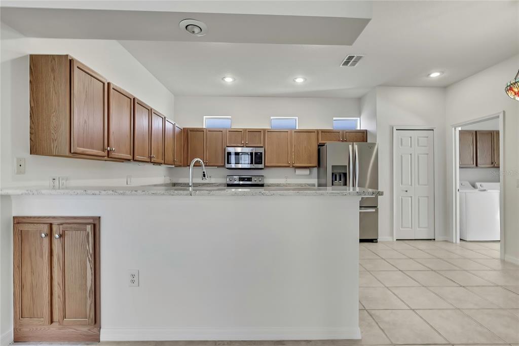 8049 Sanguinelli Road Land O Lakes, FL 34637 - Photo 9 of 45 a kitchen with stainless steel appliances granite countertop a refrigerator sink and cabinets